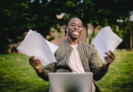 Photographs of a young man smiling and holding up documents while looking at his laptop