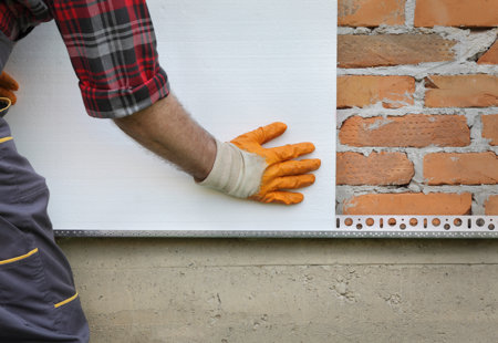 Close-up photograph of someone fitting insulation panels on a brick wall