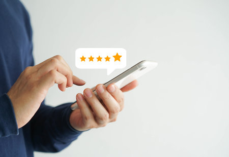 Close up of someone using a smart phone with an icon showing five stars floating over the phone