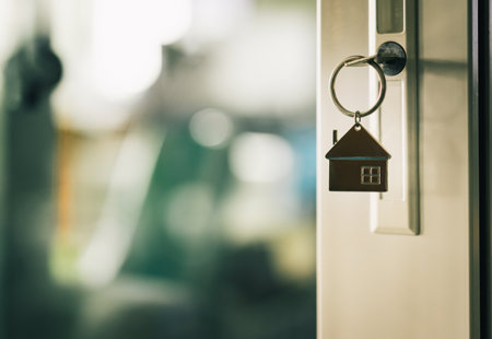Photograph of a key in a door with a keyring on it shaped like a small house