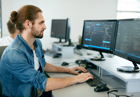 Photograph of a man working on multiple computer screens