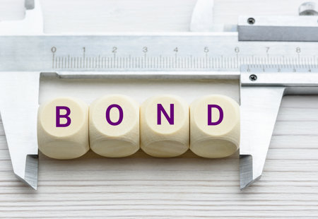 Photograph of small cubes with letters on spelling out the word 'bond' framed by some measuring calipers